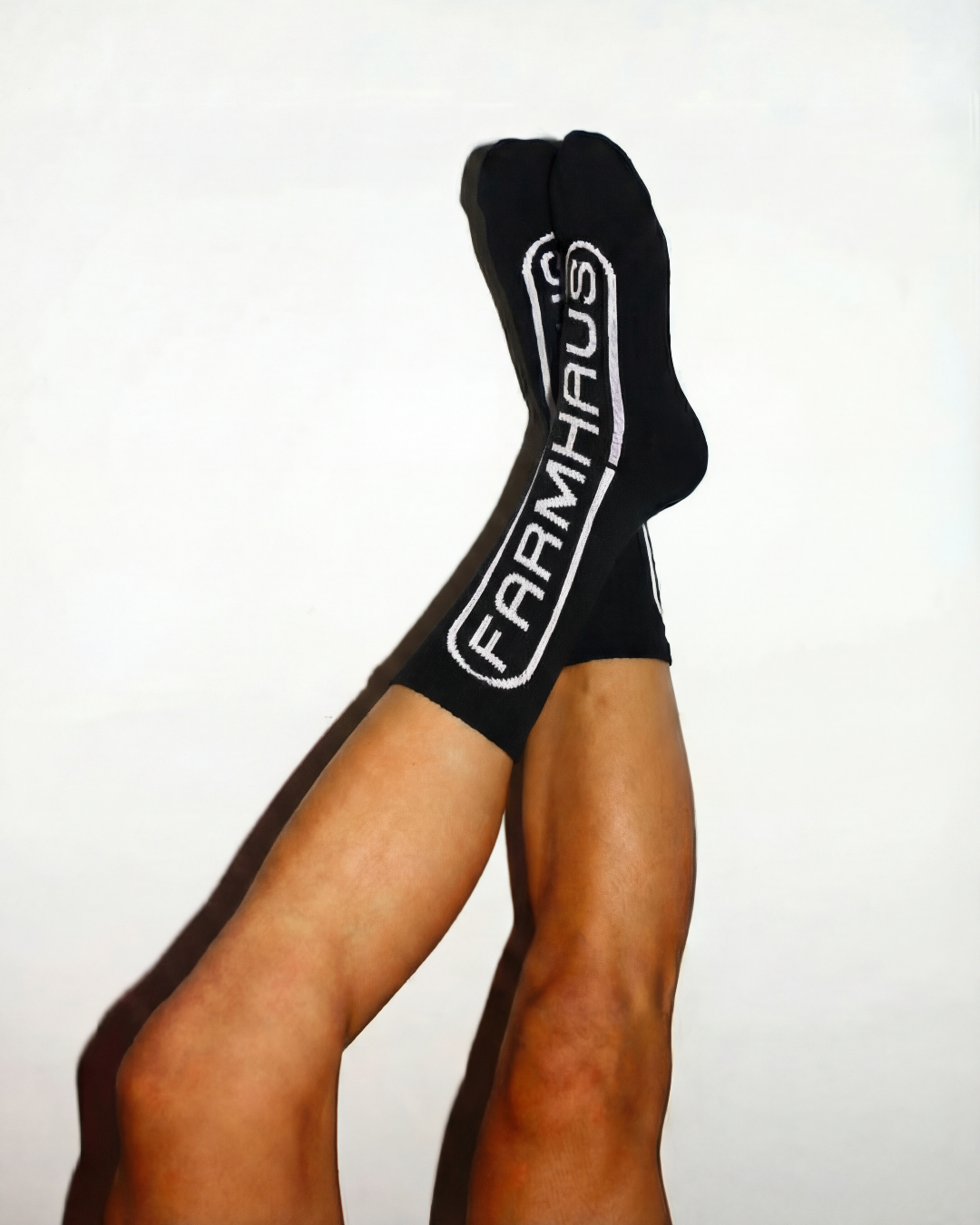Black socks with a brand logo worn by a person on a white background