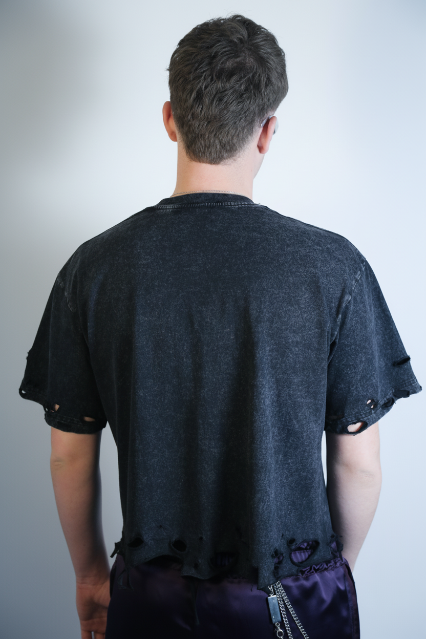 Model wearing a black distressed t-shirt against a plain background