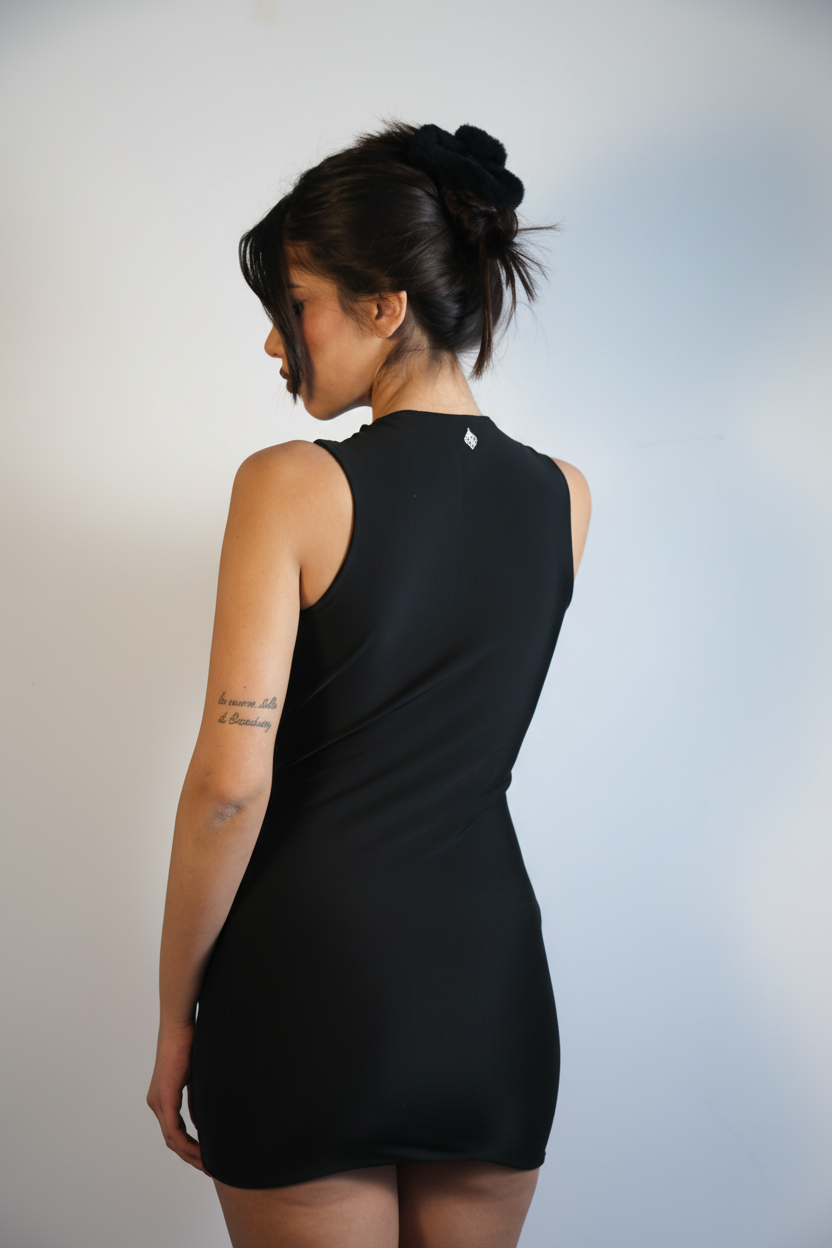 Woman wearing a black sleeveless dress against a plain background