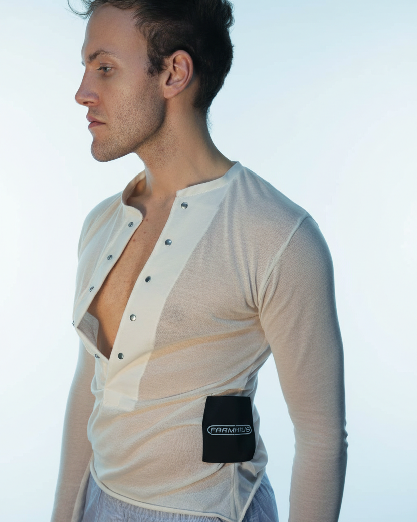 Man wearing a beige long-sleeve shirt with black buttons and a visible brand logo on a light blue background