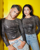 Two people wearing sparkly black long-sleeve tops and jeans against a yellow background