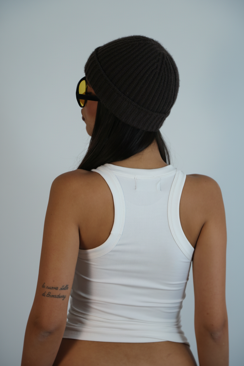 Person wearing a black beanie and white tank top on a plain background